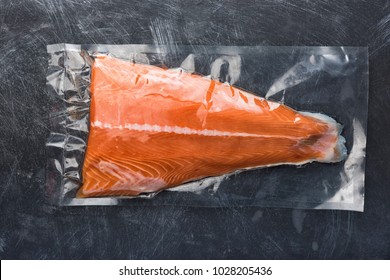 Salmon Fillet Packaged In Plastic Vacuum Pack. Fresh Fish In Packing Sell In Supermarket. Metal Black Background