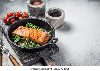 Salmon fillets, grilled steaks in skillet with herbs. White background. Top view. Copy space.