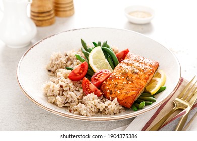 Salmon fish fillet baked, rice, green beans and tomatoes in lunch bowl. Healthy food.