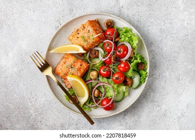 Salmon fish fillet and fresh green vegetable salad with lettuce, tomatoes, onion, mushrooms. Top view. Copy space. - Powered by Shutterstock