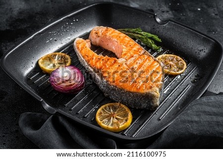 Salmon Fish Steak grilled on a grill pan with herbs. Black background. Top view