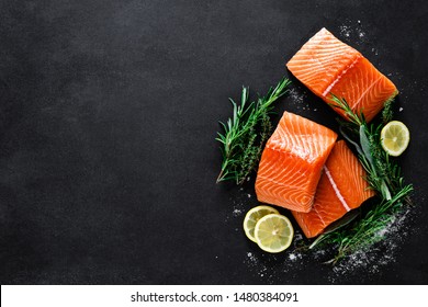 Salmon. Fresh raw salmon fish fillet with cooking ingredients, herbs and lemon on black background, top view - Shutterstock ID 1480384091