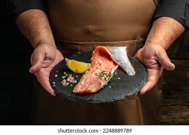 salmon is in the hands. Raw fish trout steak with spices and herbs. place for text. - Powered by Shutterstock