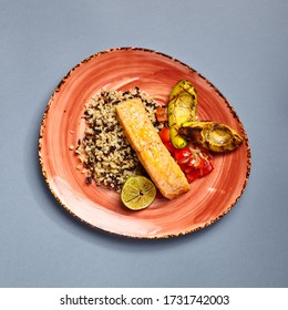 Salmon Piece With Rice And Lime Top View. Fish With Garnish. Fancy Restaurant Dish Close Up. Luxury Seafood Meal On Ceramic Peach Craft Plate. Food Presentation Art. Delicious Lunch Course