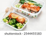 Salmon with rice and vegetables  in a glass containers made for meal prep on a light background, top view. Healthy lifestyle.