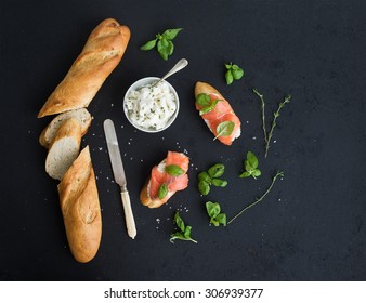 Salmon, ricotta and basil sandwiches with baguette over black grunge background. Top view, copy space - Powered by Shutterstock