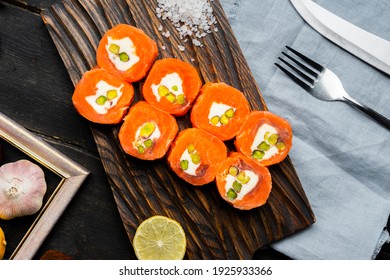 Salmon rolls with cream cheese and pistachios on a wooden cutting board. Luxury catering. Top view.
