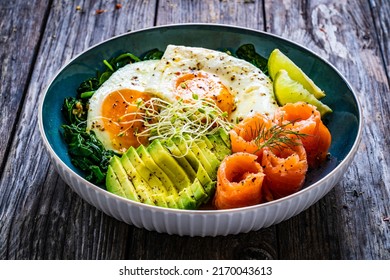 Salmon salad - smoked salmon, sunny side eggs, avocado and spinach on wooden table - Powered by Shutterstock