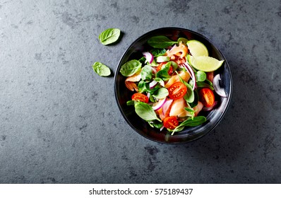 Salmon Salad with spinach, cherry tomatoes, corn salad, baby spinach, fresh mint and basil. Home made food. Concept for a tasty and healthy meal. Dark stone background. Top view. Copy space. - Shutterstock ID 575189437