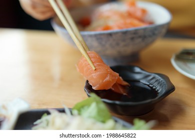 Salmon sashimi in chopsticks dipping with soy sauce - Powered by Shutterstock