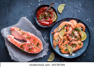 Salmon And Shrimps On Plate With Lemon, Salt, Sauce. Fish And Seafood Concept. Close-up. Top View. Big Red Prawns And Salmon For Lunch/dinner On Rustic Stone Background. Healthy Clean Eating/diet