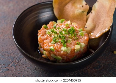 salmon Tartar with avocado on black plate on dark stone table macro close up - Powered by Shutterstock