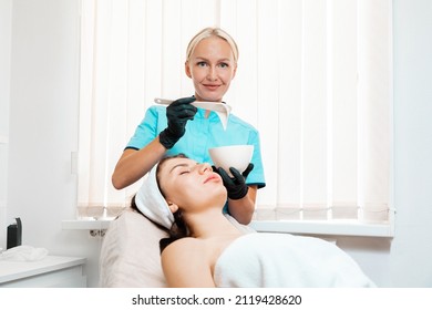 Salon beauty procedure. A cosmetologist in latex gloves prepares a rejuvenating mask for a client. The concept of professional cosmetology.