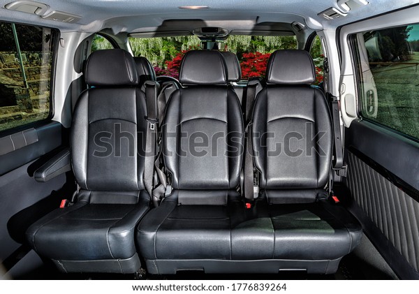 Saloon of\
the car,interior design with three leather black seats and windows\
with view to the street and\
greenery.