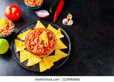 Salsa Sauce And Nacho Chips On A Dark Background. Mexican Salsa Sauce And Ingredients. Mexican Food. Copy Space. Top View