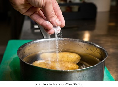 Salt Being Dropped Into A Pan Of Hot Water Containing Potatoes