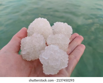 Salt From The Bottom Of The Dead Sea Held Up Against The Bright Green Sea