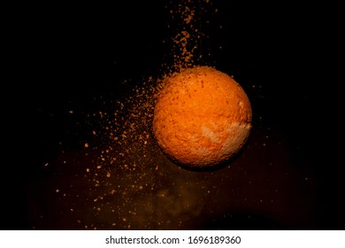 Salt falls on the orange bath ball. Bath ball with essential oils. The ball looks like a planet.