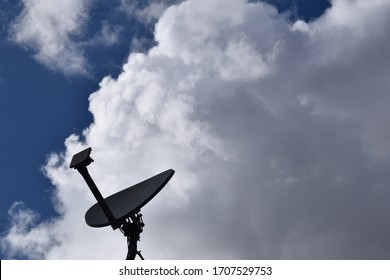 Salt Lake City, Utah / U.S.A. - April 17th 2020: DIRECTV Satellite Dish With Big Cumulus Clouds Looming Above