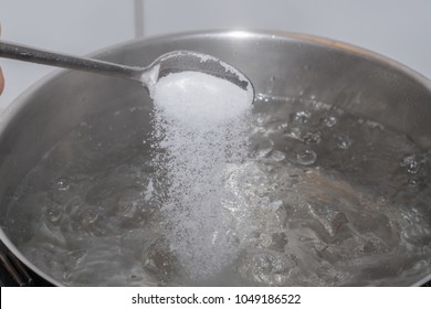 Salt On Spoon Falling On Boiling Water In Pan