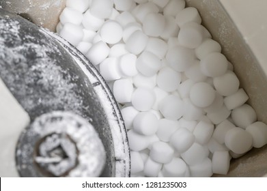 Salt pellets lies in water softener. Close-up.