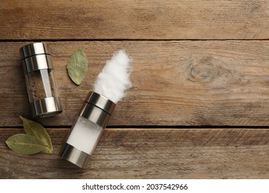 Salt And Pepper Shakers With Bay Leaves On Wooden Table, Flat Lay. Space For Text