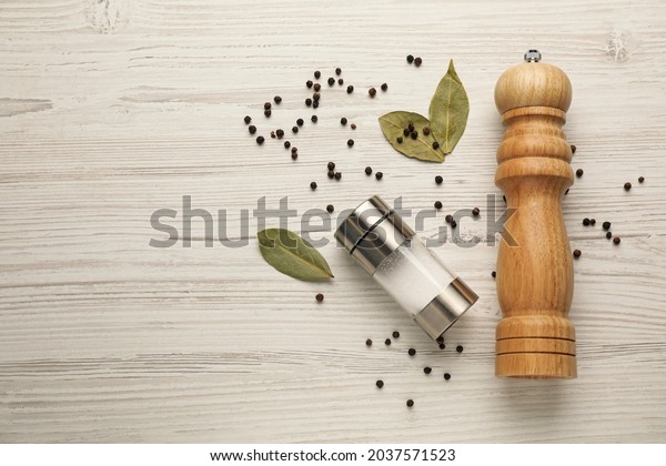 Salt and pepper shakers with bay leaves on\
white wooden table, flat lay. Space for\
text