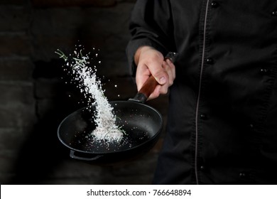 Salt Roasting In Pan With Pepper And Herbs By Chef Hands On Black Background.