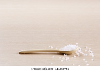 Salt in a spoon with some spilt over the wooden background with copy space - Powered by Shutterstock