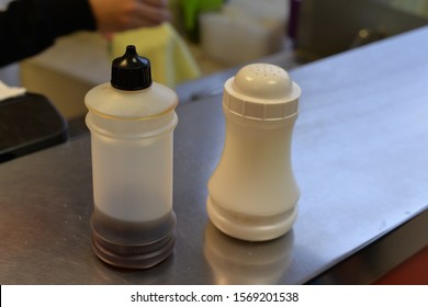 Salt and vinegar shakers on the counter in a fish and chips shop