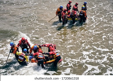 SALTBURN-BY-THE-SEA, NORTH YORKSHIRE / UK - June 09, 2019: Mountain Rescue Team Volunteers Training With Drowning Casualty In Inflatable Stretcher In Sea, Preparing For Emergency Service Ocean Rescue.