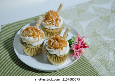 Salted Caramel Cupcake With Flower Garnish On A White Plate