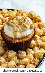 Salted Caramel Cupcake Sitting On Cake Stand With Caramel Popcorn - Light Background