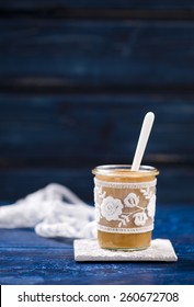 Salted Caramel Sauce In A Glass Jar On A Wooden Desk