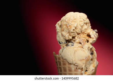 Salted Caramel Truffle Ice Cream In Waffle Cone On Dark Red Background