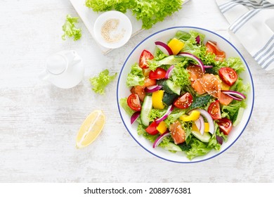 Salted salmon salad with fresh green lettuce, cucumbers, tomato, bell pepper and red onion. Ketogenic, keto or paleo diet lunch bowl. Top view - Shutterstock ID 2088976381