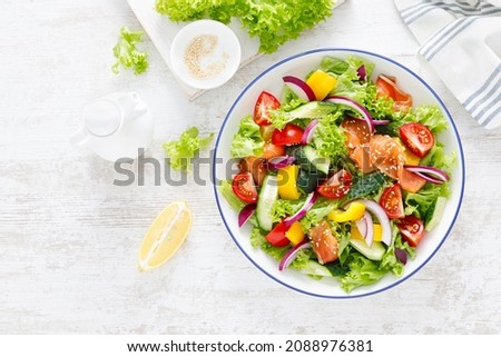 Salted salmon salad with fresh green lettuce, cucumbers, tomato, bell pepper and red onion. Ketogenic, keto or paleo diet lunch bowl. Top view