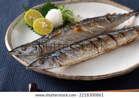 Salt-grilled pacific saury, garnished with grated daikon radish and a wedge of lemon. Sanma, Japanese grilled fish.