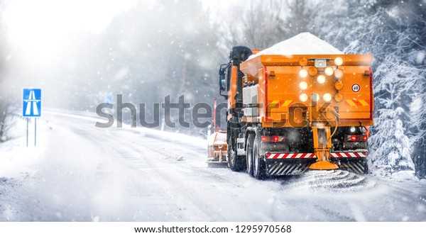Salting highway maintenance. Snow plow truck on\
snowy road in action. Hard weather condition in winter. Gritter\
vehicle spreading deicing\
salt.