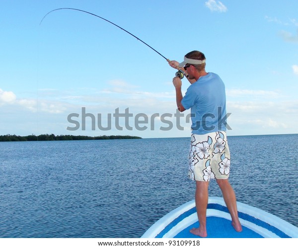 Saltwater fly fishing for bonefish -\
Fighting a big fish in the ocean off the front of a\
boat