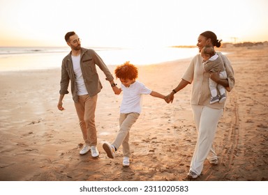 Salty air, family fair. Happy family walking with their children on vacation on the beach by seaside, parents enjoying evening time with kids outdoors - Shutterstock ID 2311020583