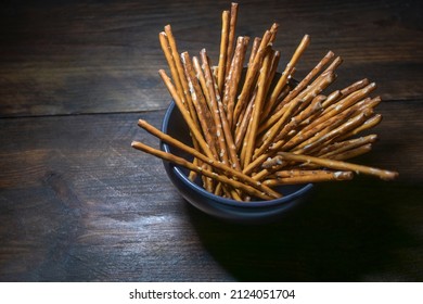 Salty Pretzel Sticks In A Bowl On A Dark Rustic Wooden Table, Crunchy Snack Food Often Served In The Evening In Pubs Or At Home While Watching TV, Copy Space, Selected Focus, Narrow Depth Of Field