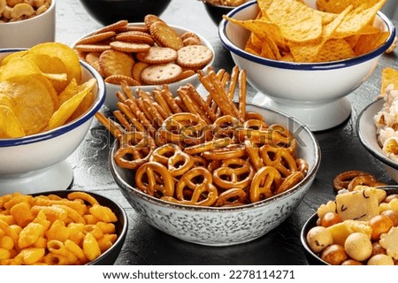 Salty snacks, party mix. An assortment of crispy appetizers in bowls on a table. Potato and tortilla chips, crackers, popcorn etc