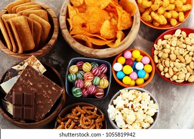 Salty snacks. Pretzels, chips, crackers in wooden bowls. Unhealthy products. food bad for figure, skin, heart and teeth. Assortment of fast carbohydrates food.  - Shutterstock ID 1055819942