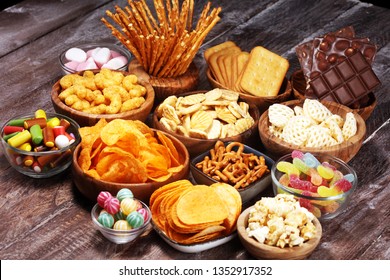 Salty snacks. Pretzels, chips, crackers in wooden bowls. Unhealthy products. food bad for figure, skin, heart and teeth. Assortment of fast carbohydrates food.  - Shutterstock ID 1352917352