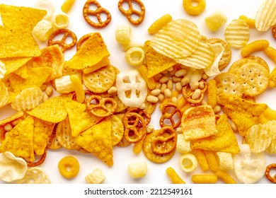 Salty Snacks Texture On A White Background. Party Food Assorted Mix. Potato And Tortilla Chips, Crackers And Other Appetizers, Overhead Flat Lay Shot