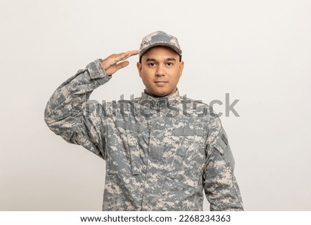 Saluting Asian man special forces soldier standing in studio. Commander Army soldier military defender of the nation in uniform standing on white background.