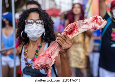 Salvador, Bahia, Brazil - April 09, 2022: A Woman Protesting Against Far-right Presidential Candidate Jair Bolsonaro, With Bovine Bone In Her Hands Symbolizing Hunger.