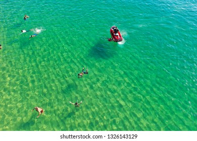 SALVADOR, BAHIA, BRAZIL - FEB 26, 2019: Porto Da Barra Beach, People Swimming On A Beautiful Emerald Green Water. 