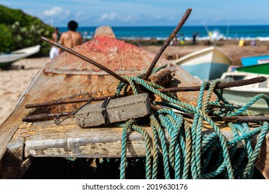 Salvador, Bahia, Brazil - May 23, 2021: Imported Fishing Boat With Anchor And Ropes On Top. People Passing By. Boca Do Rio Beach.